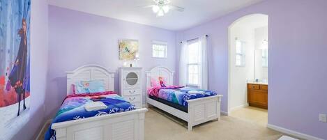 A bedroom with two beds, a ceiling fan, and a small table with a remote control.