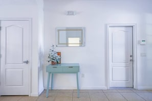 A hallway with two white doors, a light blue console table with a mirror above it, and a small decorative plant. - Solterra Resort Pool House 6BR/Sleeps 12 (Davenport)