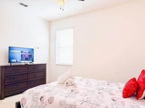 A bedroom with a bed, a television on a dresser, and a window with blinds. - Solterra Resort Pool House 6BR/Sleeps 12 (Davenport)