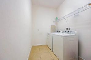 A laundry room with two white washing machines, a drying rack, and a towel on the wall. - Solterra Resort Pool House 6BR/Sleeps 12 (Davenport)