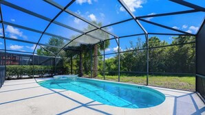 Une piscine entour ée d’une terrasse en béton et dotée d’une paroi en verre.