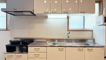 A kitchen with a stainless steel sink, a stove, and beige cabinets with gold handles.