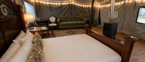Eine Zelthütte mit einem Bett, einer Couch, einem Tisch und einem Kamin.
