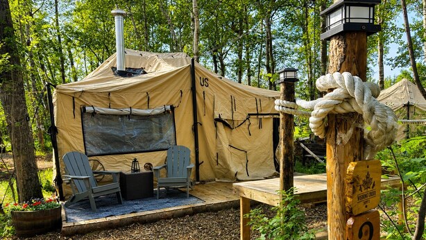 A camping site with a tent, two chairs, a table, and a lantern.