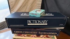 A stack of board games on a wooden table.