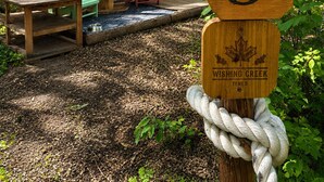 Tienda señalizada con 'Wishing Creek Tent 5', con un poste de madera y una cuerda.