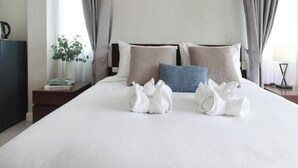 A hotel room with a neatly made bed, a bedside table with a lamp, and a chair.