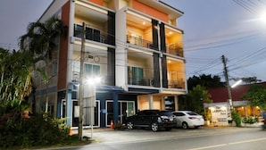 A multi-story hotel with balconies, a parking area, and a sign for 'The Langstan Suites.'