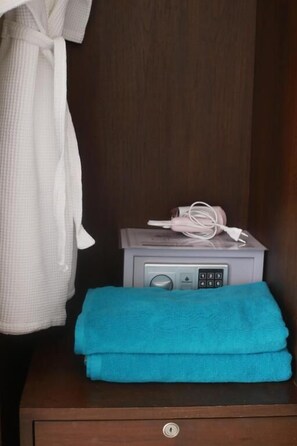 A wooden nightstand with a radio, a white robe, and a blue towel. - The Zen Suites (Rawai)