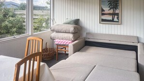 A cozy room with a sofa, a chair, a table, and a window with a view of greenery. - Nice home in Assens with WiFi (Assens)