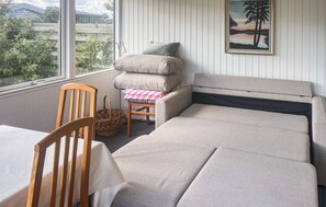 Ein gemütliches Zimmer mit einer Couch, einem Sessel, einem Tisch und einem Fenster mit Blick auf Grünflächen.