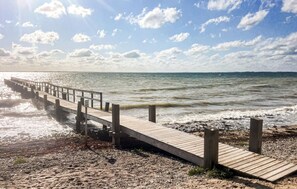 Eine Holzstege, der sich ins Meer erstreckt, mit einer felsigen Küstenlinie.