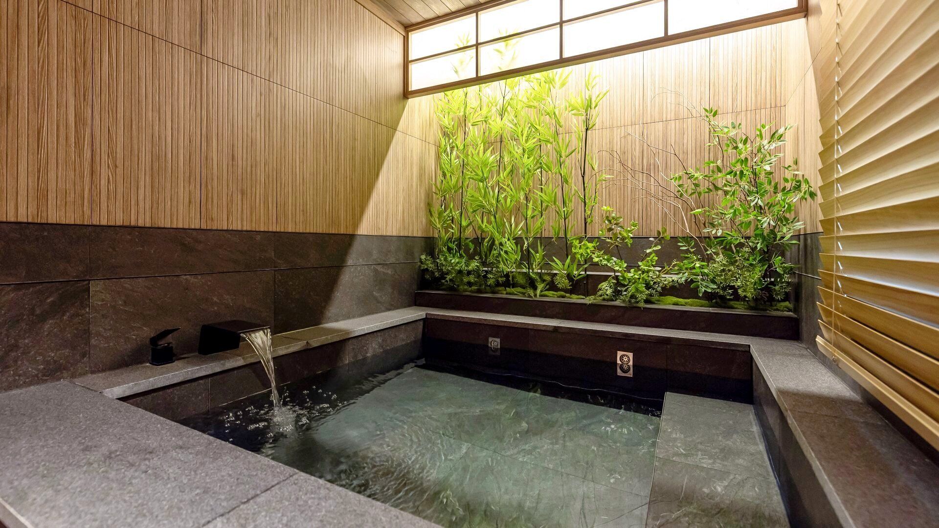 Un jacuzzi con un muro de cañas de bambú y una ventana con persianas.