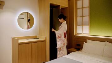 Una habitación de hotel con una cama, una mesita de noche con teléfono, un espejo y un armario de madera.