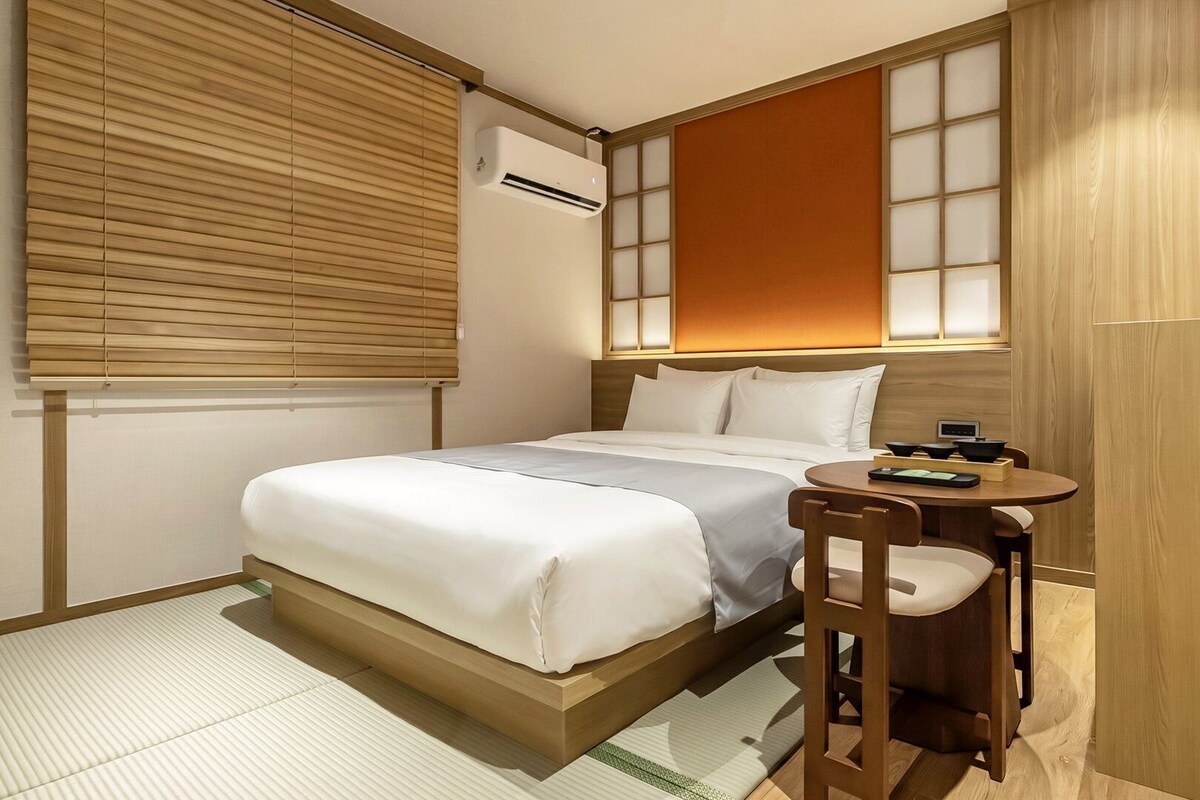 Una habitación de hotel con cama, mesita de noche y una pequeña mesa con sillas.