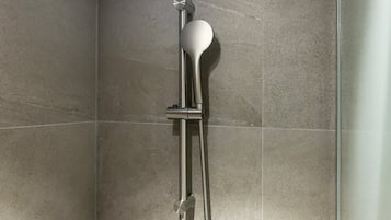 Una ducha con cabezal de ducha de mano y manguera flexible.
