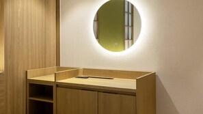 Un baño con tocador de madera, un espejo y una lámpara.