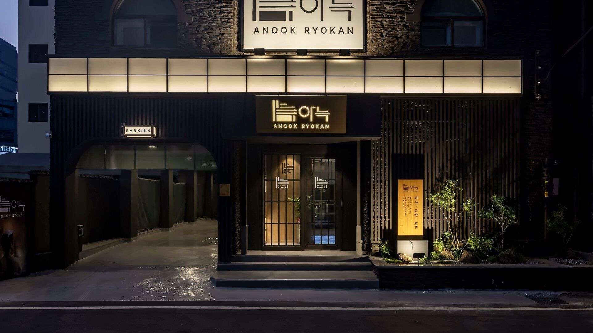 Un edificio con un letrero que dice 'ANOOK RYOKAN' y una señal de estacionamiento.