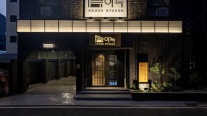 A building with a sign that reads 'ANOOK RYOKAN' and a parking sign.