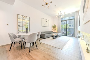 Ein modernes Wohnzimmer mit Essbereich, einem grauen Sofa, einem runden Couchtisch und einem Balkon mit Blick.