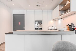 Eine moderne Küche mit einer zentralen Kochinsel, eingebauten Geräten und Blick in den Wohnbereich.