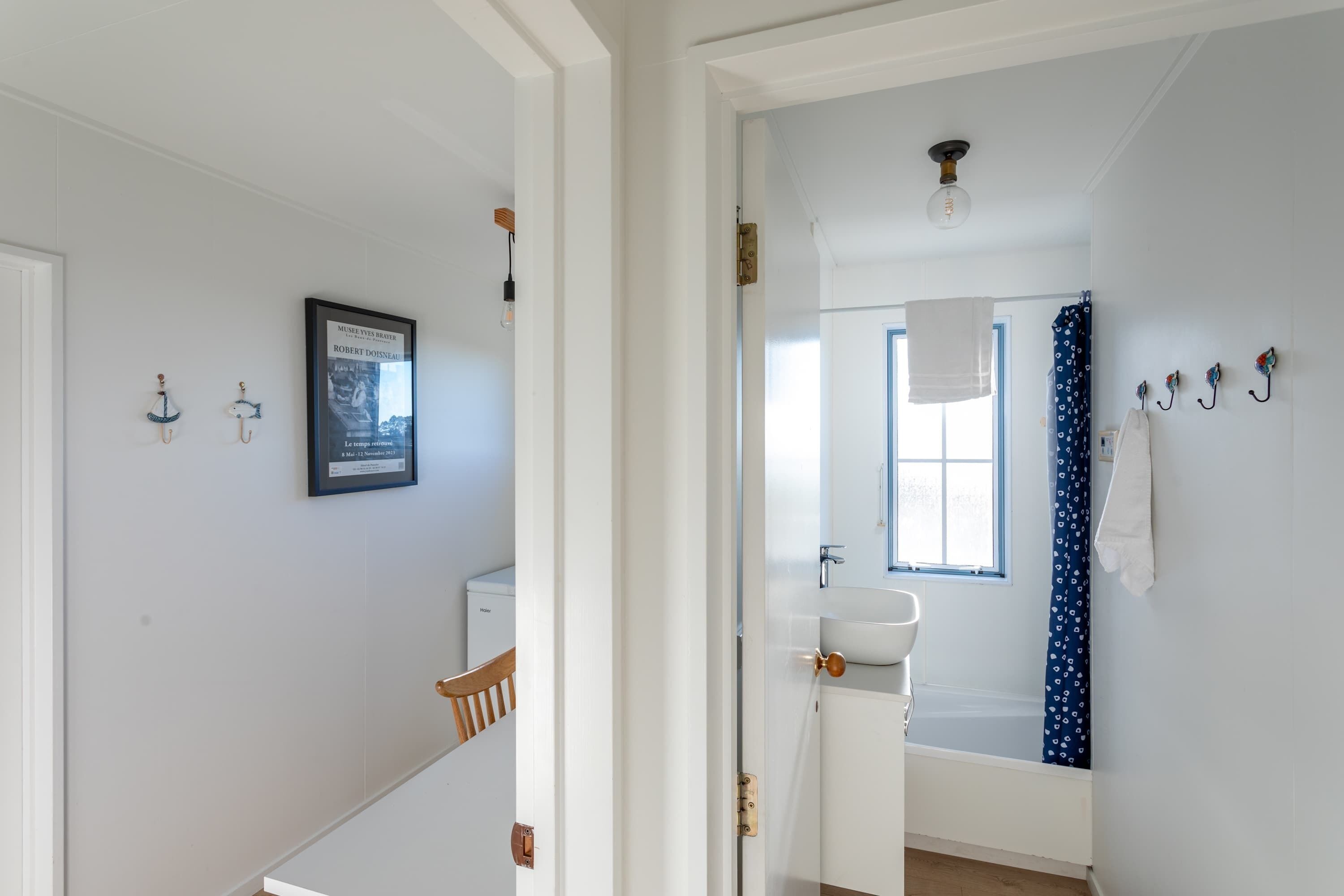A hallway leading to a bathroom with a white sink, a mirror, and a shower curtain.
