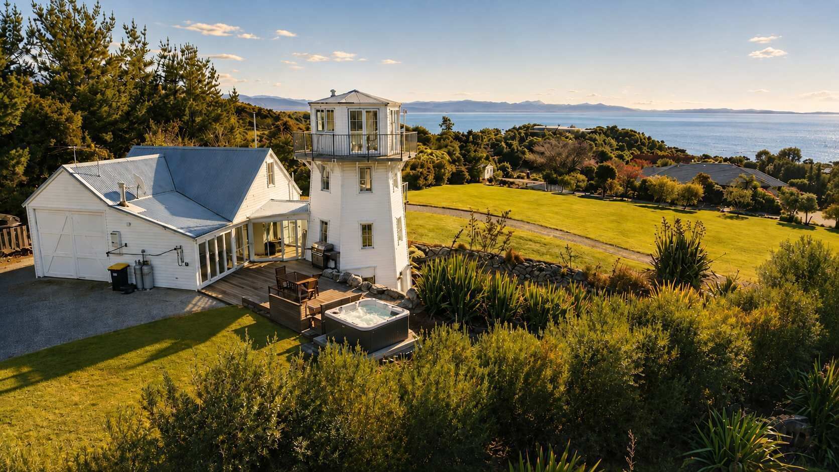 A white building with a tower, a deck, and a hot tub.
