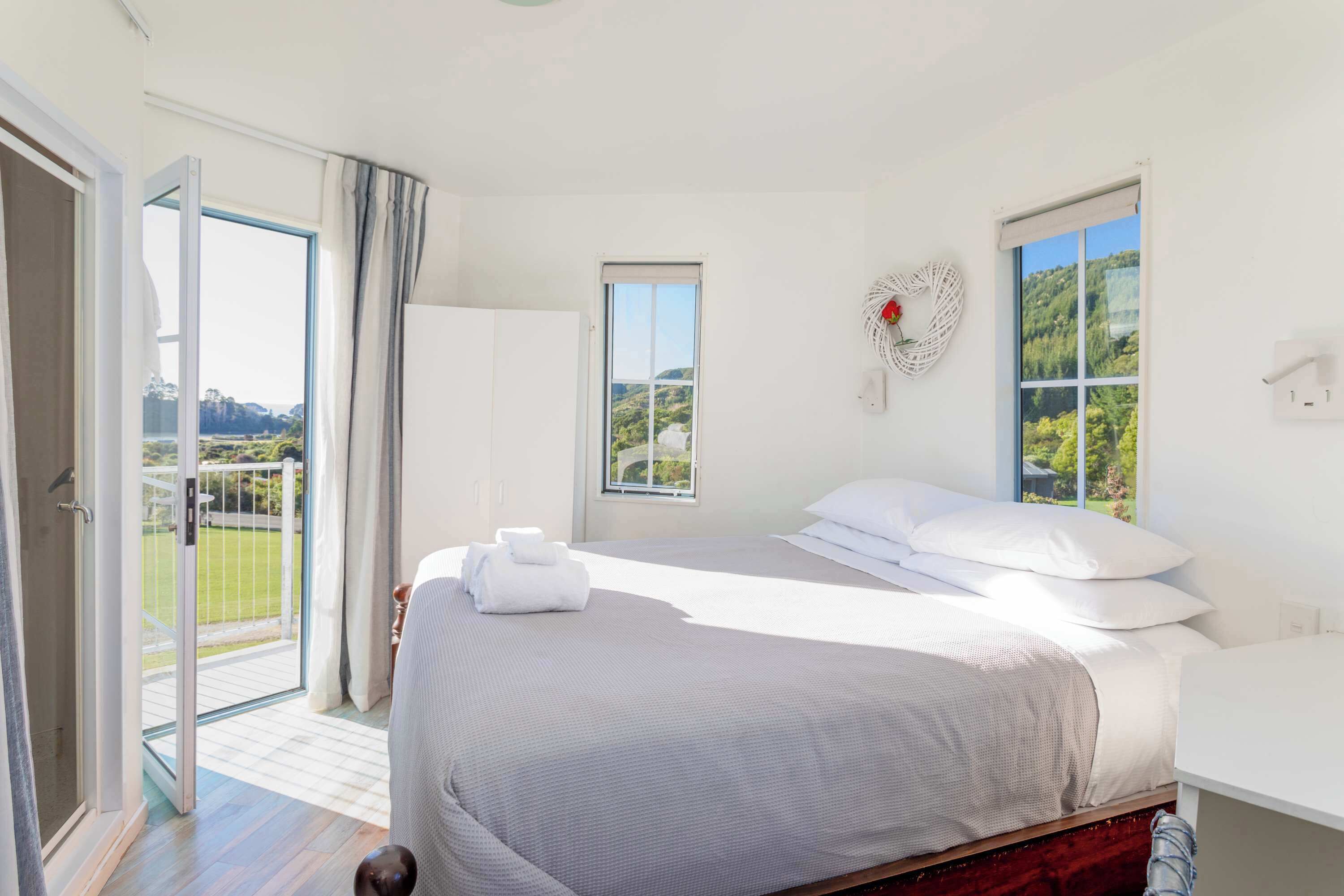 Quarto de hotel com uma cama, janela com vista, porta para uma varanda e interruptor de luz na parede.
