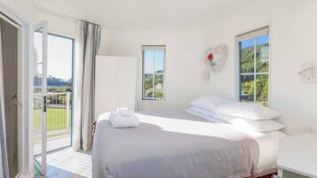 Ein Hotelzimmer mit einem Bett, einem Fenster mit Blick, einer Tür, die auf einen Balkon führt, und einem an der Wand befestigten Lichtschalter.