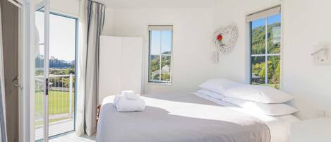 Quarto de hotel com uma cama, janela com vista, porta para uma varanda e interruptor de luz na parede.