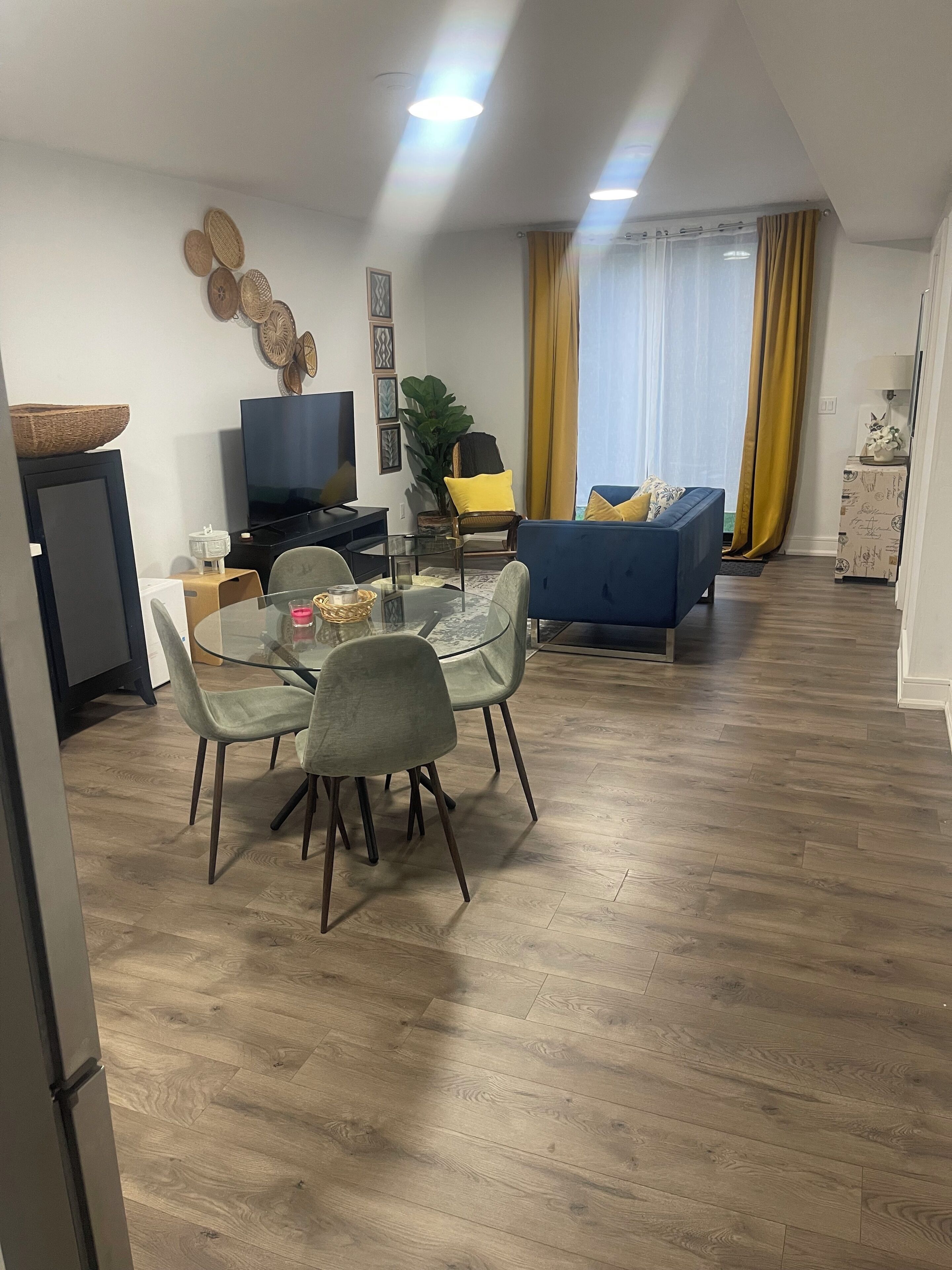 A modern living room with a dining area, a television, and a sofa.