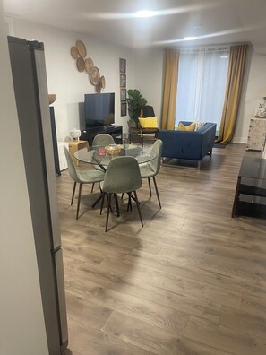 Un salon moderne comprenant un coin repas, un téléviseur à écran plat et un canapé bleu.