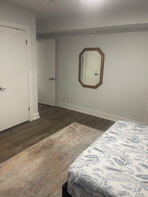 Une chambre à coucher avec un lit, un tapis, une porte et un miroir au mur.