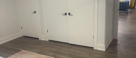 A bedroom with a bed, a large closet, and a view into another room.