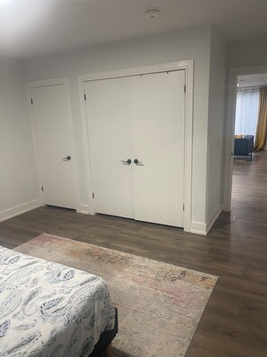 A bedroom with a bed, a large closet, and a view into another room. - Private spacious bedroom with ensuite and living space (Oshawa)