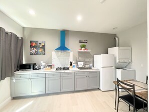 Eine moderne Küche mit grauen Schränken, einer eingebauten Mikrowelle, einem Gasherd und einem weißen Kühlschrank.