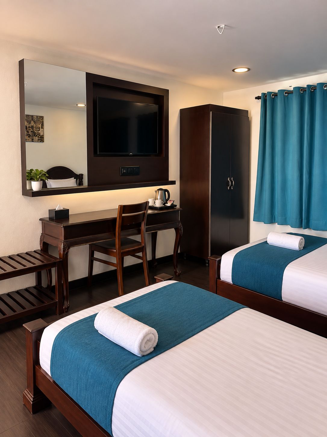 Ein Hotelzimmer mit zwei Betten, einem Schreibtisch, einem Fernseher, einem Kleiderschrank und einem Badezimmer mit Duschvorhang.