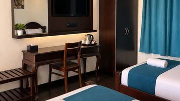 Ein Hotelzimmer mit zwei Betten, einem Schreibtisch, einem Fernseher, einem Kleiderschrank und einem Badezimmer mit Duschvorhang.