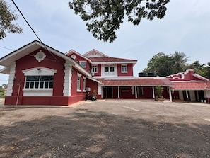 A two-story building with a red facade and a covered porch area.