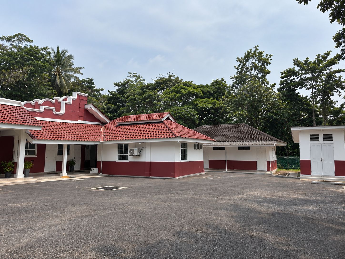 A building with a red and white color scheme, multiple doors, and a parking area in front.