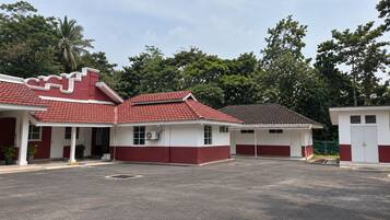 A building with a red and white color scheme, multiple doors, and a parking area in front.