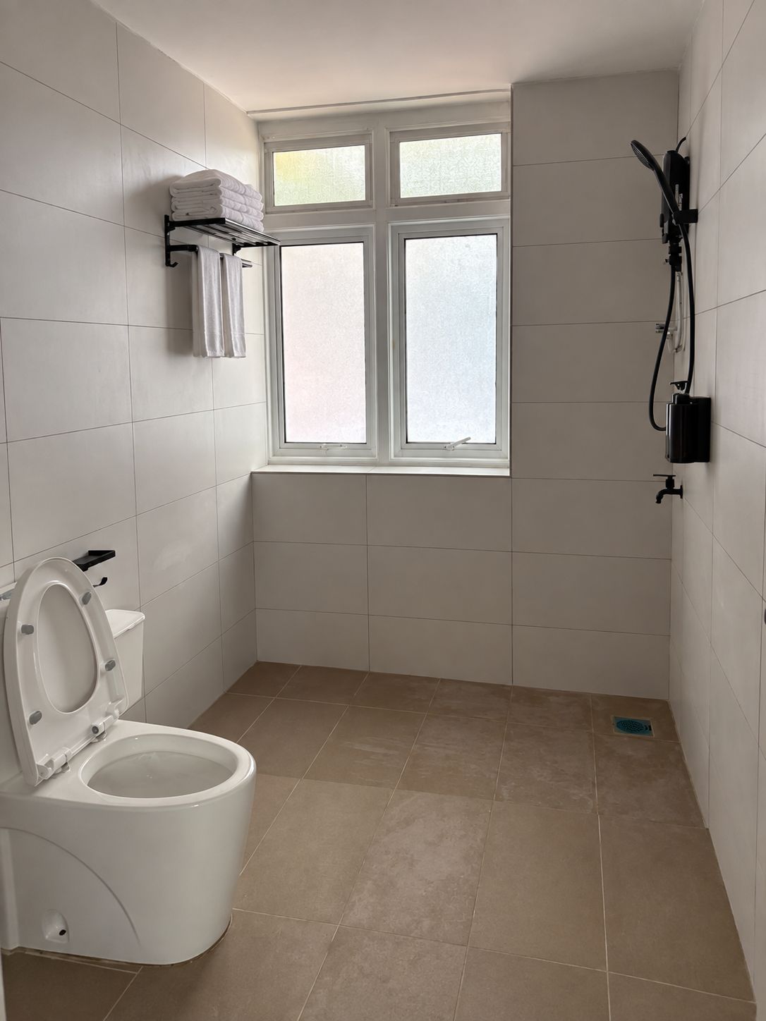 A bathroom with a toilet, a window, and a towel rack.