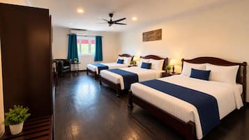 A hotel room with two beds, a ceiling fan, and a window with curtains.