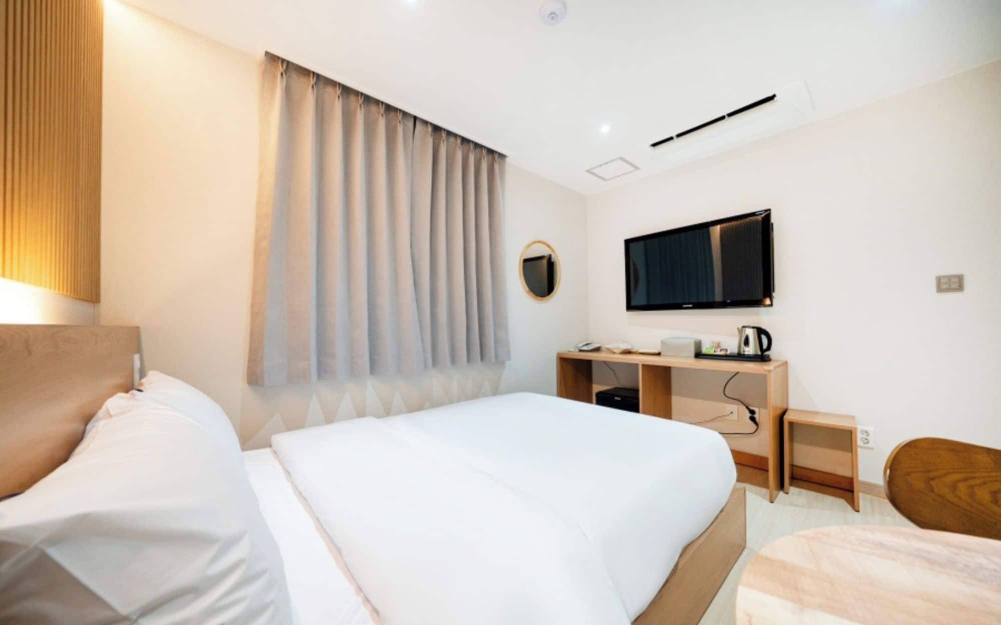 Une chambre d’hôtel avec un lit, un bureau, une télévision et une chaise.
