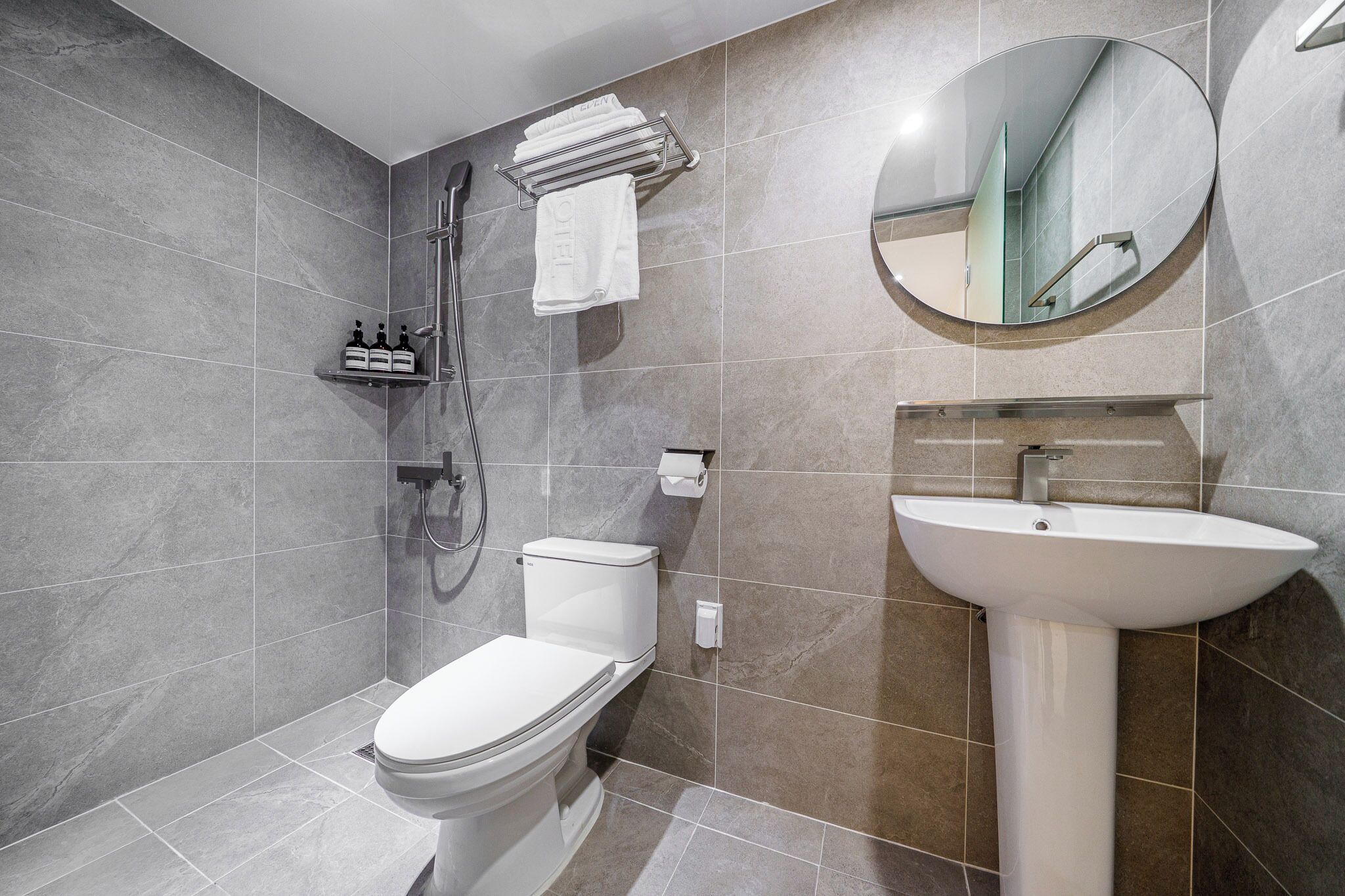 Une salle de bain moderne équipée de toilettes, d’une douche et d’un lavabo.
