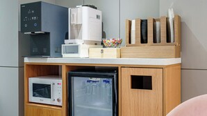 A kitchenette with a coffee maker, microwave, and refrigerator.