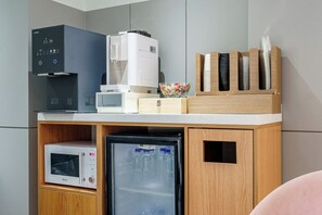 Una kitchenette equipada con cafetera, microondas y refrigerador.