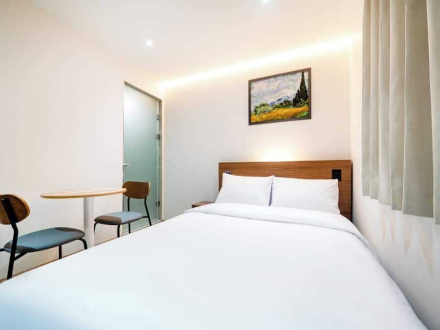 A hotel room with a bed, a desk, and a chair.