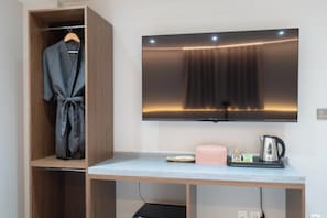 A room with a wooden wardrobe, a flat-screen TV mounted on the wall, a small table with a kettle and a pink candle. - Hotel Eden at Kyunghee Univ (Seoul)