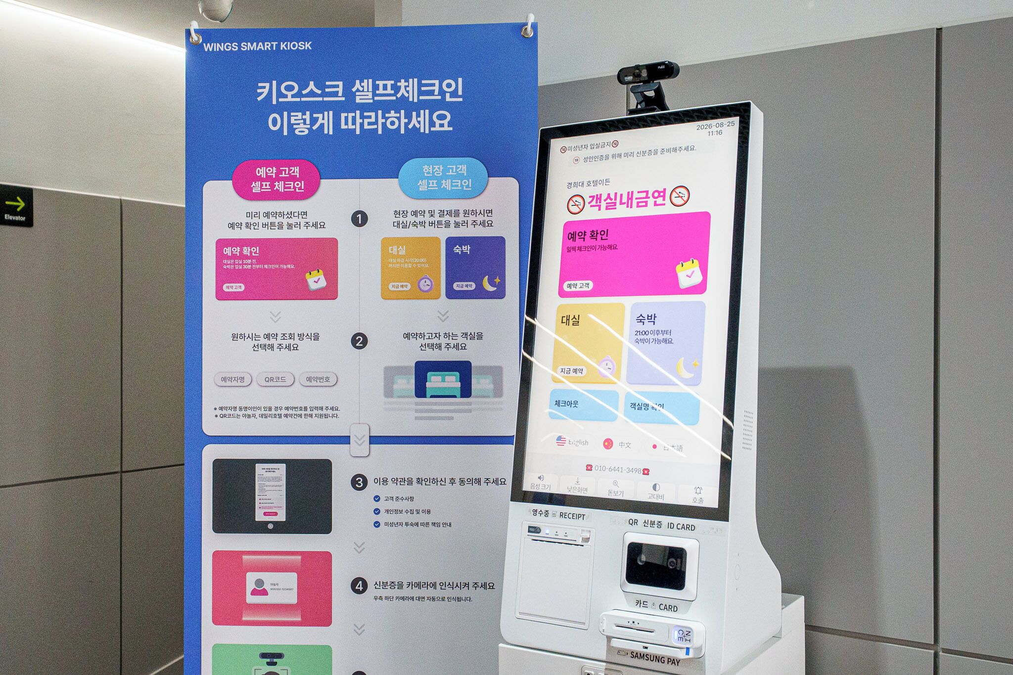 A kiosk with a digital display and a poster with instructions in Korean.